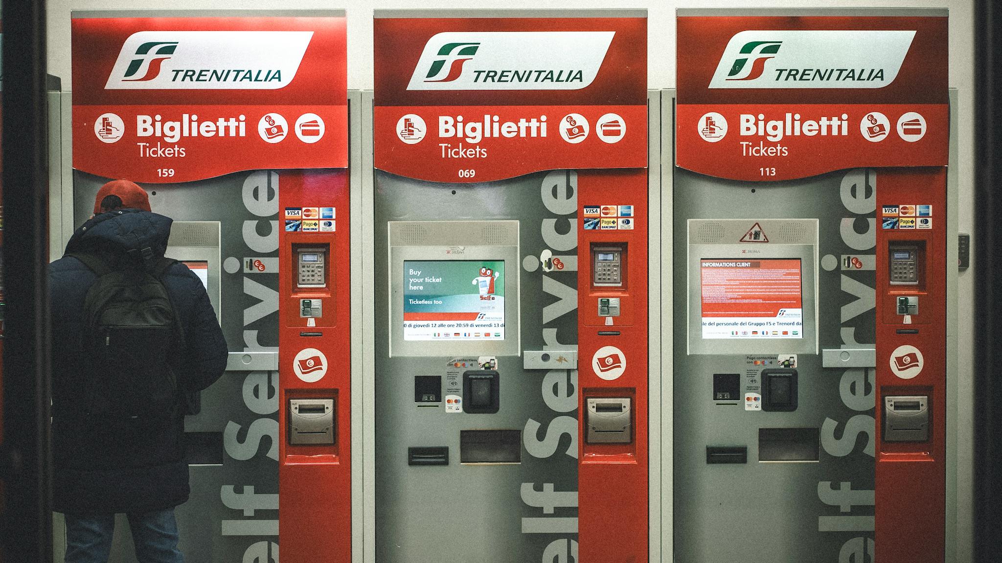 A traveler uses Trenitalia ticket machines at a station in Florence, Italy.