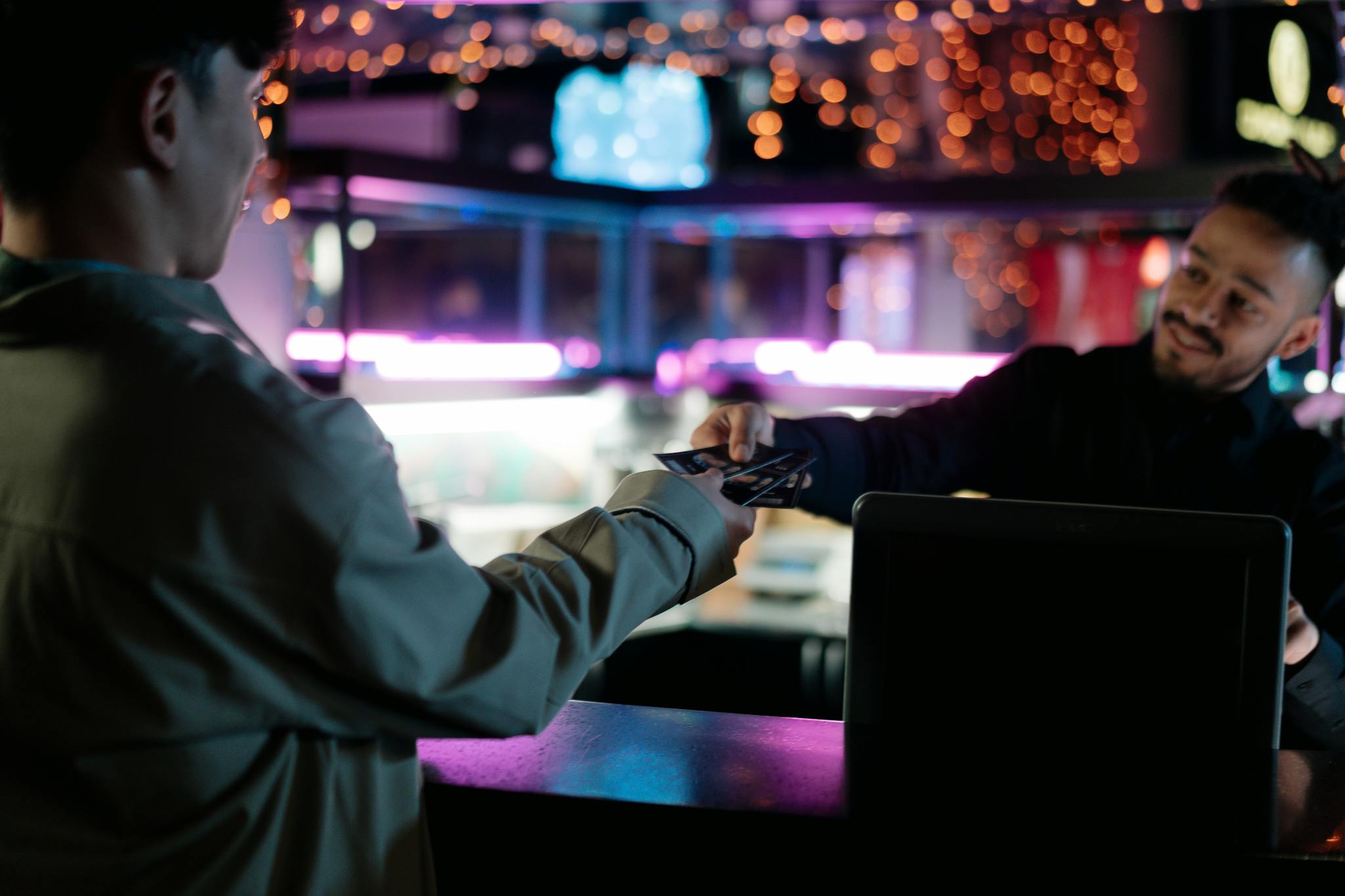 Man smiling while handing over and receiving tickets at a kiosk counter.