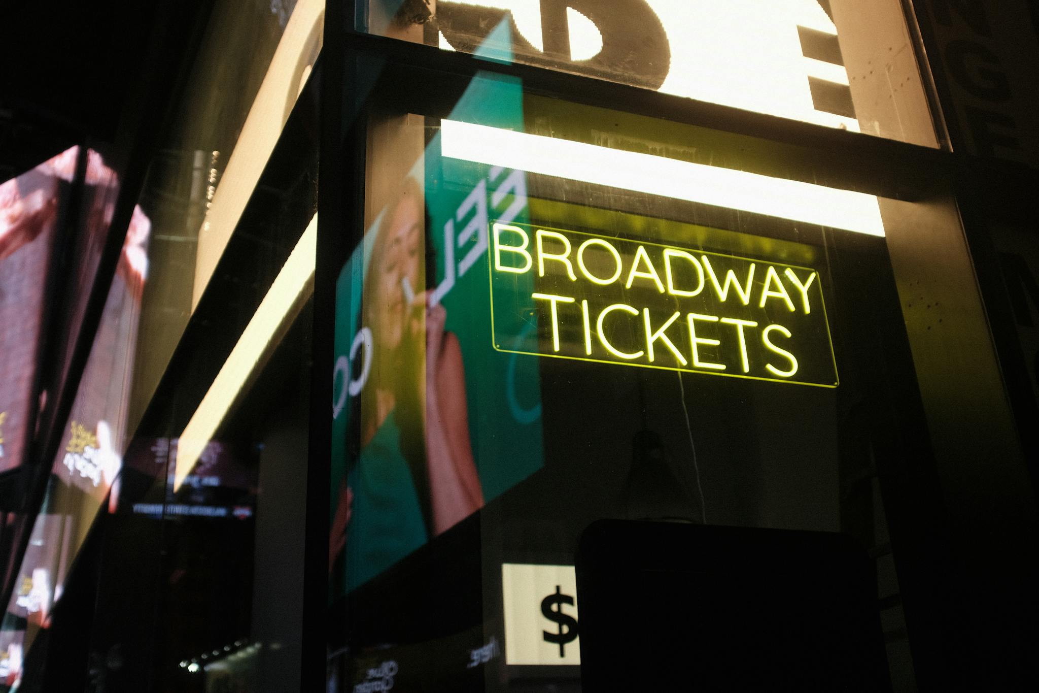 Vibrant neon Broadway tickets sign in New York City at night, capturing urban nightlife atmosphere.